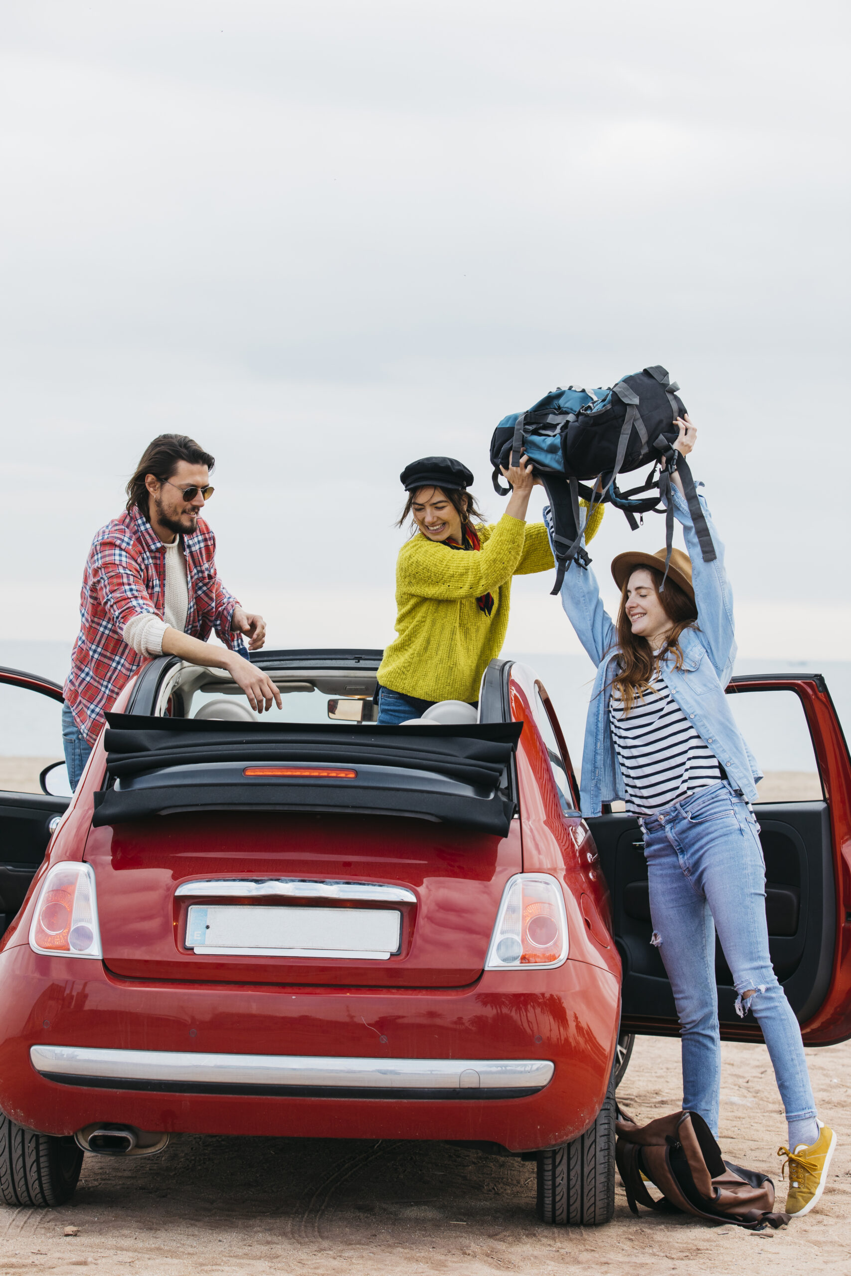 woman giving backpack lady near man leaning out from car